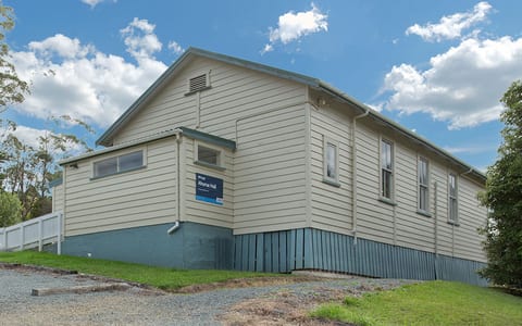 Weatherboard community hall exterior with signage and gravel car park