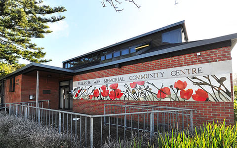 Brick community centre building with painted poppy mural across the facade