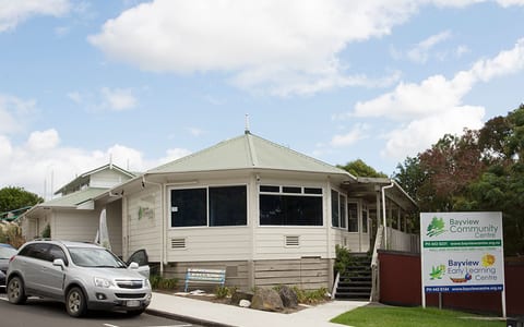 Single-storey weatherboard community centre with a bay-window extension and signage on the street