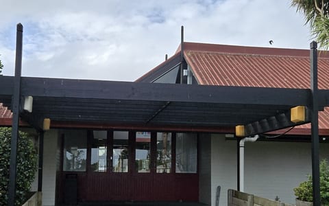 Low community centre building with red corrugated roof and covered entrance
