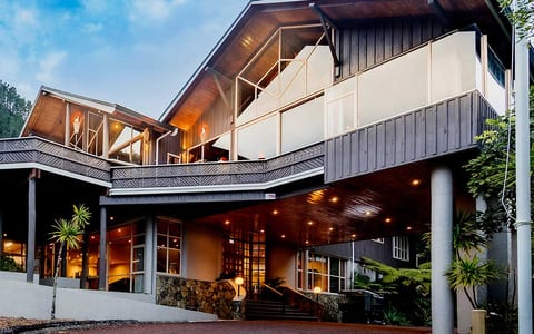 Multi-level resort building with decks lit at dusk amid trees