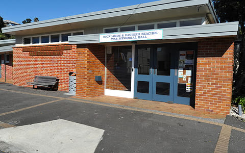 Single-storey brick hall with blue entrance doors and signage above
