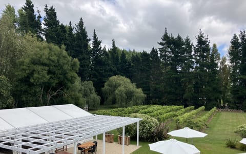Outdoor venue grounds with marquee structure, pergola, lawn, and trees