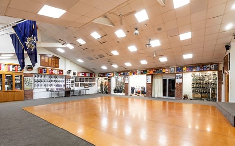 Large function room with dance floor, trophies on display, and club memorabilia on walls