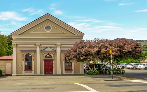 Cream rendered heritage building with classical columns, triangular pediment, red double doors