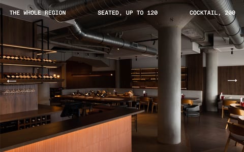 Industrial-style dining room with concrete columns, backlit wine racks, and timber banquettes
