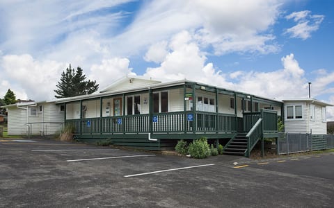 White weatherboard community house building with green veranda and car park