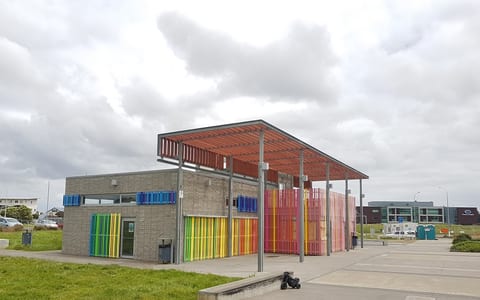 Contemporary concrete block activity centre with coloured vertical screen panels and covered entry
