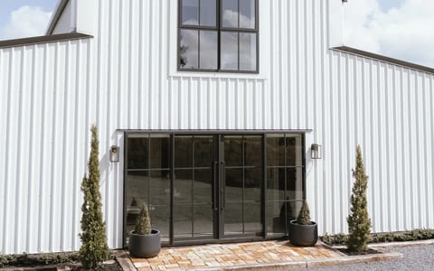 White steel barn building with black-framed glazed entry doors