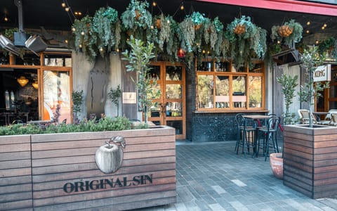 Restaurant exterior with hanging greenery, timber planter box with branding, and outdoor seating