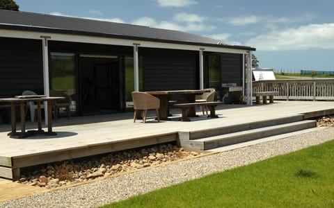 Dark-clad building with timber deck, outdoor furniture and lawn