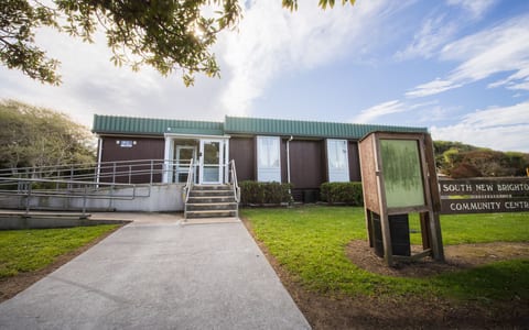 Single-storey community hall with green corrugated cladding and ramp entrance