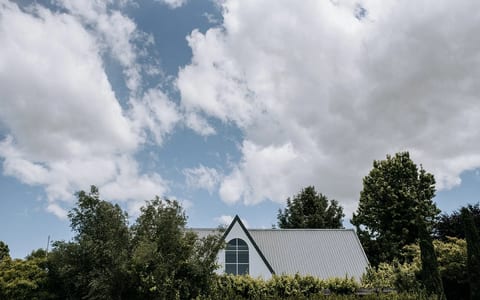 White metal-roofed building partially visible above trees against a cloudy sky