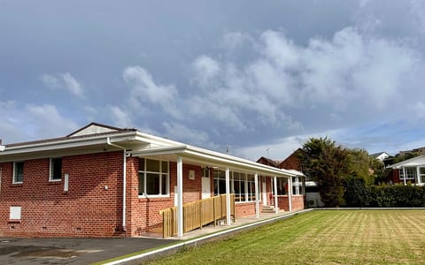 Single-storey brick clubhouse building with covered veranda and lawn