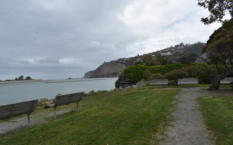 Grassed reserve with benches alongside an estuary and headland
