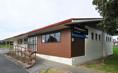 Single-storey community hall with red roof trim and accessible ramp