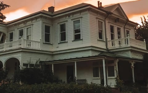 Heritage homestead exterior at dusk with warm sky and veranda detail