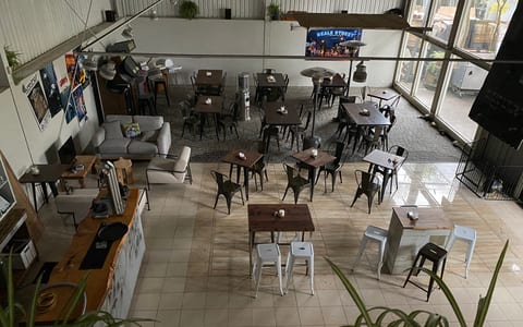 Industrial dining space viewed from above with metal chairs, wooden tables, and mezzanine