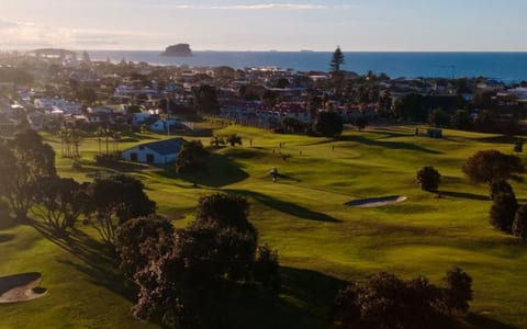 Aerial view of golf course fairways with coastal town and sea beyond