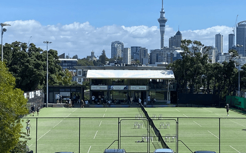 Tennis courts with pavilion building and Auckland city skyline behind