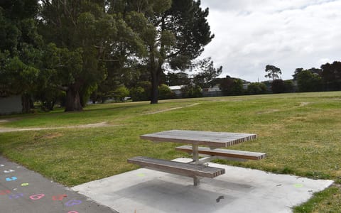 Park with picnic table, trees and painted pathway markings in foreground