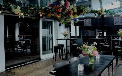 Outdoor terrace set with black tables and flower arrangements for an event