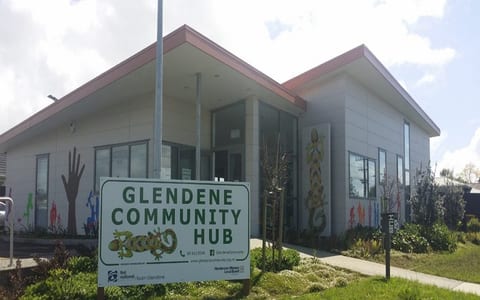 Modern community hub building with mural artwork and entry sign