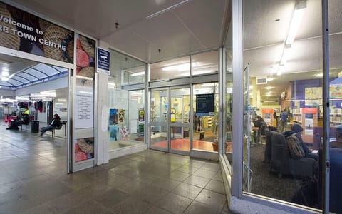 Library entrance viewed from covered walkway with signage visible inside