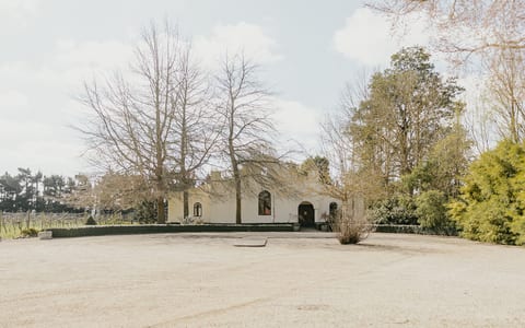 White rendered venue building with arched windows surrounded by bare deciduous trees and vines