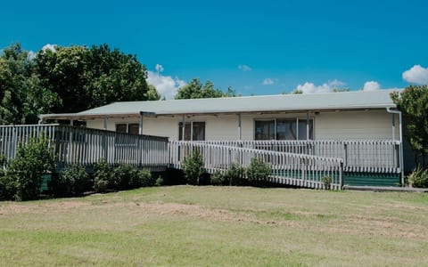 Single-storey weatherboard hall with veranda and grass lawn