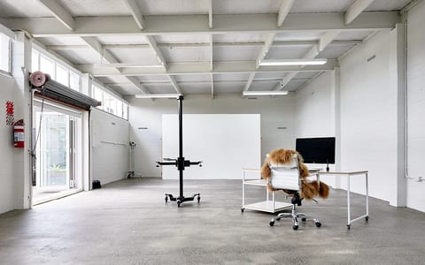 Open white industrial space with concrete floor, photography backdrop and desk