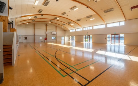 Large sports hall with curved timber roof and polished floor