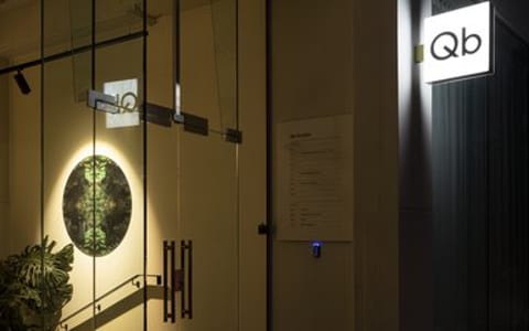 Illuminated glass entry at night with Qb signage on dark building facade