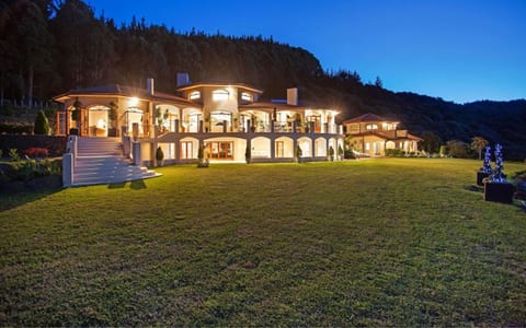 Mediterranean-style two-storey venue lit at night with arched colonnades against dark hills