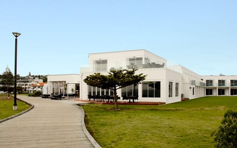 White hotel building exterior with lawn and boardwalk approach
