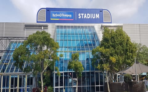 Stadium building facade with large glazed entrance and branded signage above