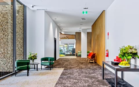 Contemporary foyer corridor with stone wall, timber slat partition, and colourful lounge chairs