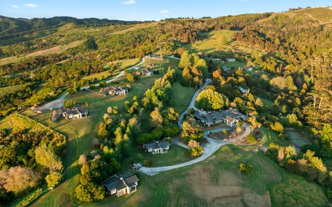 Aerial view of scattered dark-roof lodges across rolling green hills and woodland