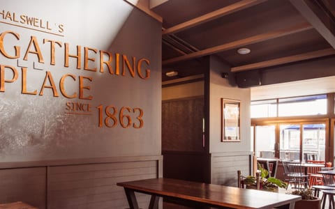 Pub bar area with branded mural wall, timber tables and booth seating