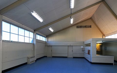 Plain hall interior with blue vinyl floor, angled ceiling and service counter