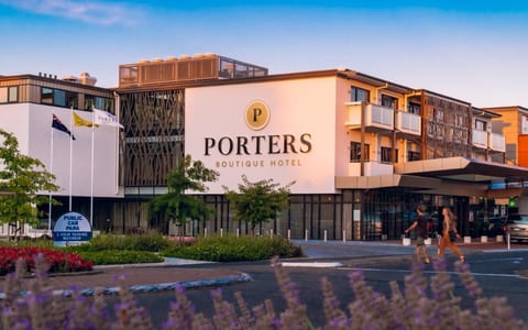 Contemporary multi-storey hotel with timber-screen facade, signage and landscaped forecourt at dusk