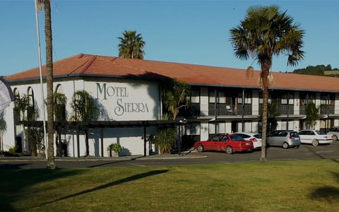Two-storey motel building with parking area and palm trees in foreground