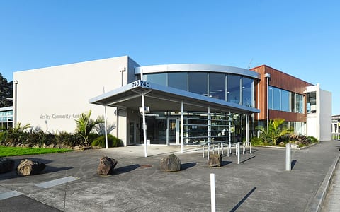 Modern community centre building with curved glazed facade and corten cladding