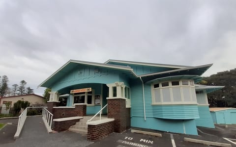 Painted weatherboard bungalow in teal with verandah and car park