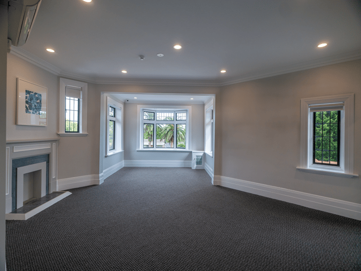 Carpeted room with bay window, fireplace and open-plan layout