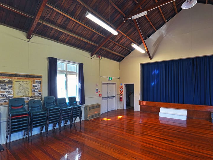Hall interior with timber ceiling, polished timber floor, and blue curtained stage