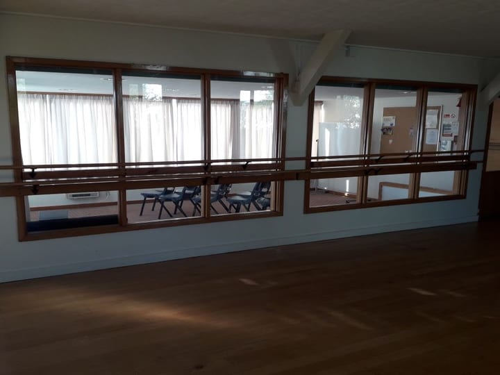 Empty hall with timber floor, mirrors, and views into adjoining carpeted room