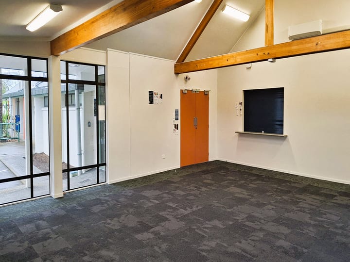 Empty hall room with timber-beam ceiling and orange door