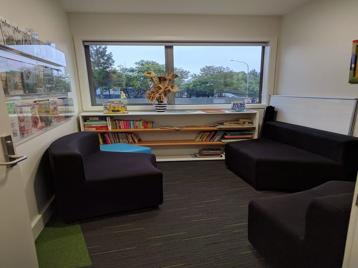 Community reading nook with curved sofas, children's books, and window view