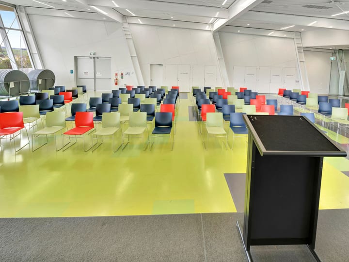 Large hall with coloured seating rows, lectern and angled ceiling
